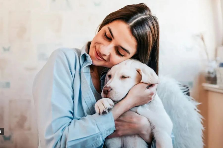 Do Dogs Have a Sixth Sense and Do They Know When Something Bad Is About to Happen? 4 A young woman hugs a sleepy Labrador puppy with a serene smile, capturing the deep human-dog bond that raises the question Do Dogs Have a Sixth Sense.